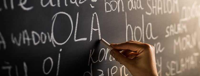 Hand writing greetings in other languages on a blackboard