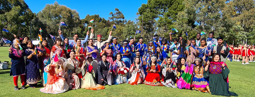 A group of people of different cultures wearing traditional costumes and holding flags 