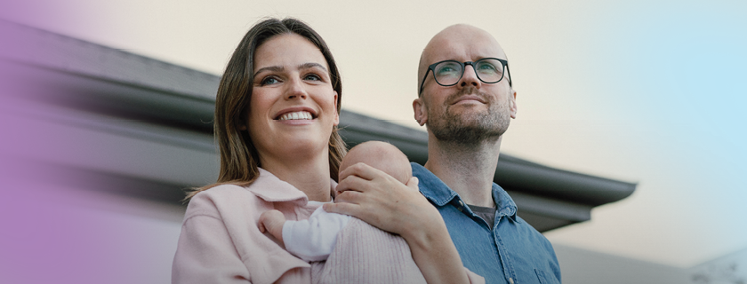 Woman holding a baby and a man looking off into the distance.