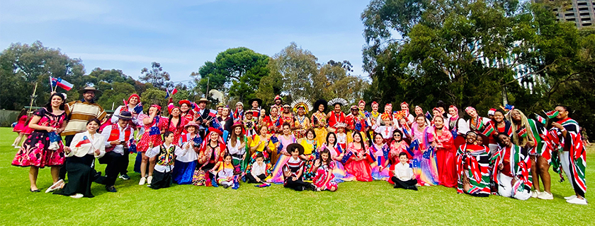 Large group of pageant participants wearing brightly coloured clothing representing many different cultures
